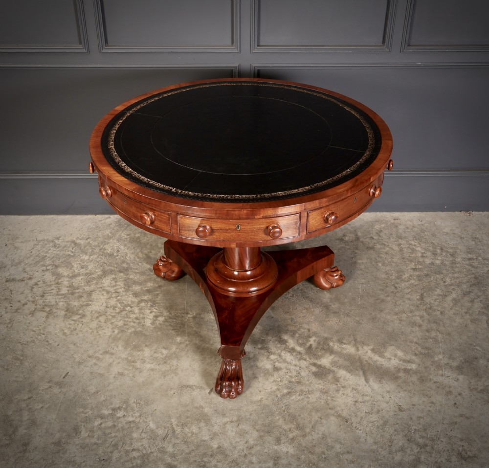 A circular William IV mahogany rotating drum table featuring a black leather inset top, frieze drawers with turned handles, a thick turned column, and a triform base with carved paw feet. View VIII
