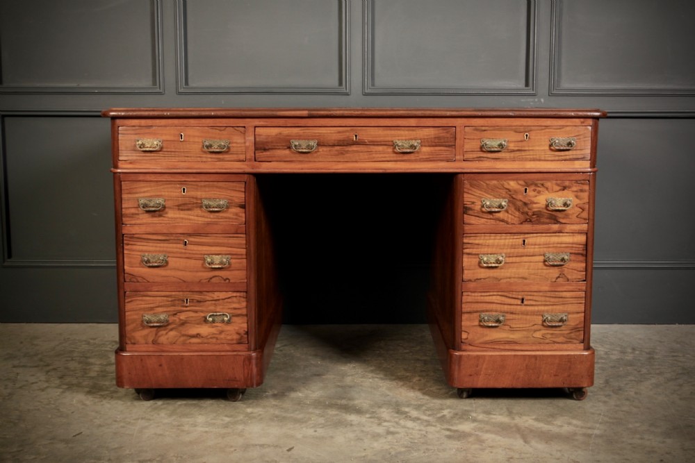 A nineteenth-century Victorian walnut pedestal desk featuring an inset green leather writing surface, twin drawer pedestals, and brass drop handles. View IV
