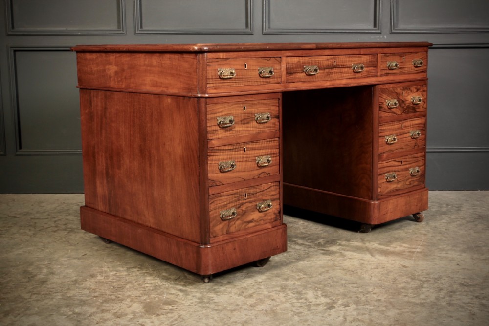 A nineteenth-century Victorian walnut pedestal desk featuring an inset green leather writing surface, twin drawer pedestals, and brass drop handles. View II