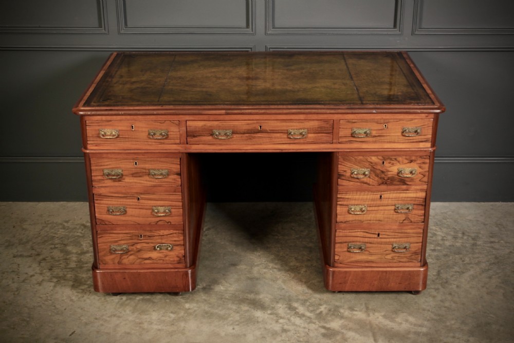 A nineteenth-century Victorian walnut pedestal desk featuring an inset green leather writing surface, twin drawer pedestals, and brass drop handles. View III