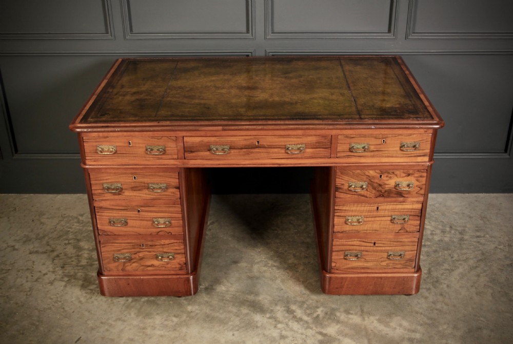 A nineteenth-century Victorian walnut pedestal desk featuring an inset green leather writing surface, twin drawer pedestals, and brass drop handles. View V