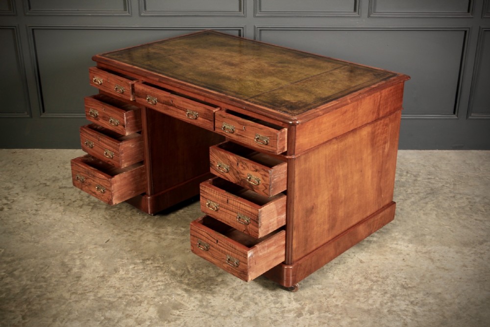 A nineteenth-century Victorian walnut pedestal desk featuring an inset green leather writing surface, twin drawer pedestals, and brass drop handles. View VII