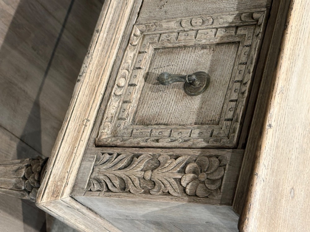 A long carved bleached oak potboard dresser base featuring relief carved drawer fronts, turned support legs, brass drop handles, and an open lower display shelf. View X