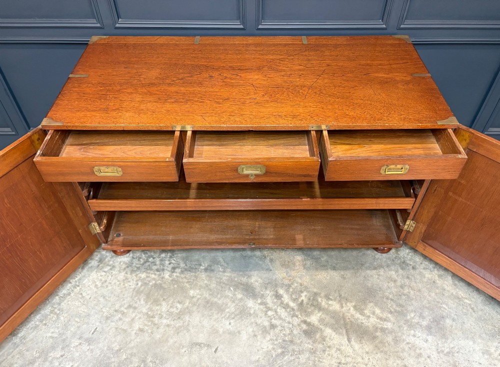 A low Victorian teak military campaign side cabinet featuring double panelled doors, brass corner mounts, brass side handles, and short turned feet. View VIII
