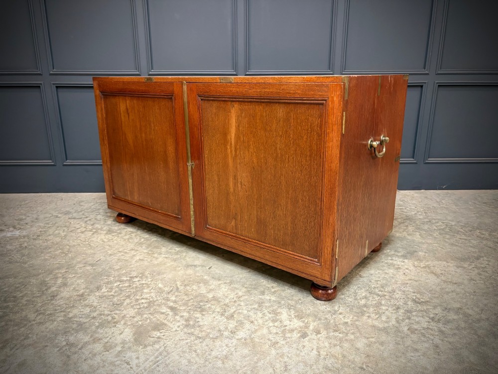 A low Victorian teak military campaign side cabinet featuring double panelled doors, brass corner mounts, brass side handles, and short turned feet. View IX