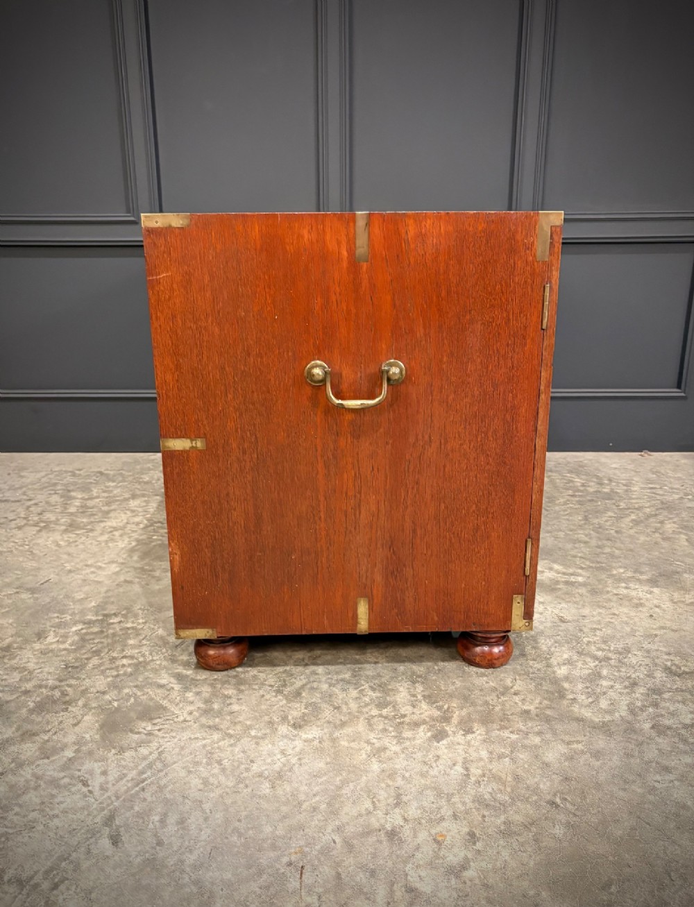 A low Victorian teak military campaign side cabinet featuring double panelled doors, brass corner mounts, brass side handles, and short turned feet. View XII