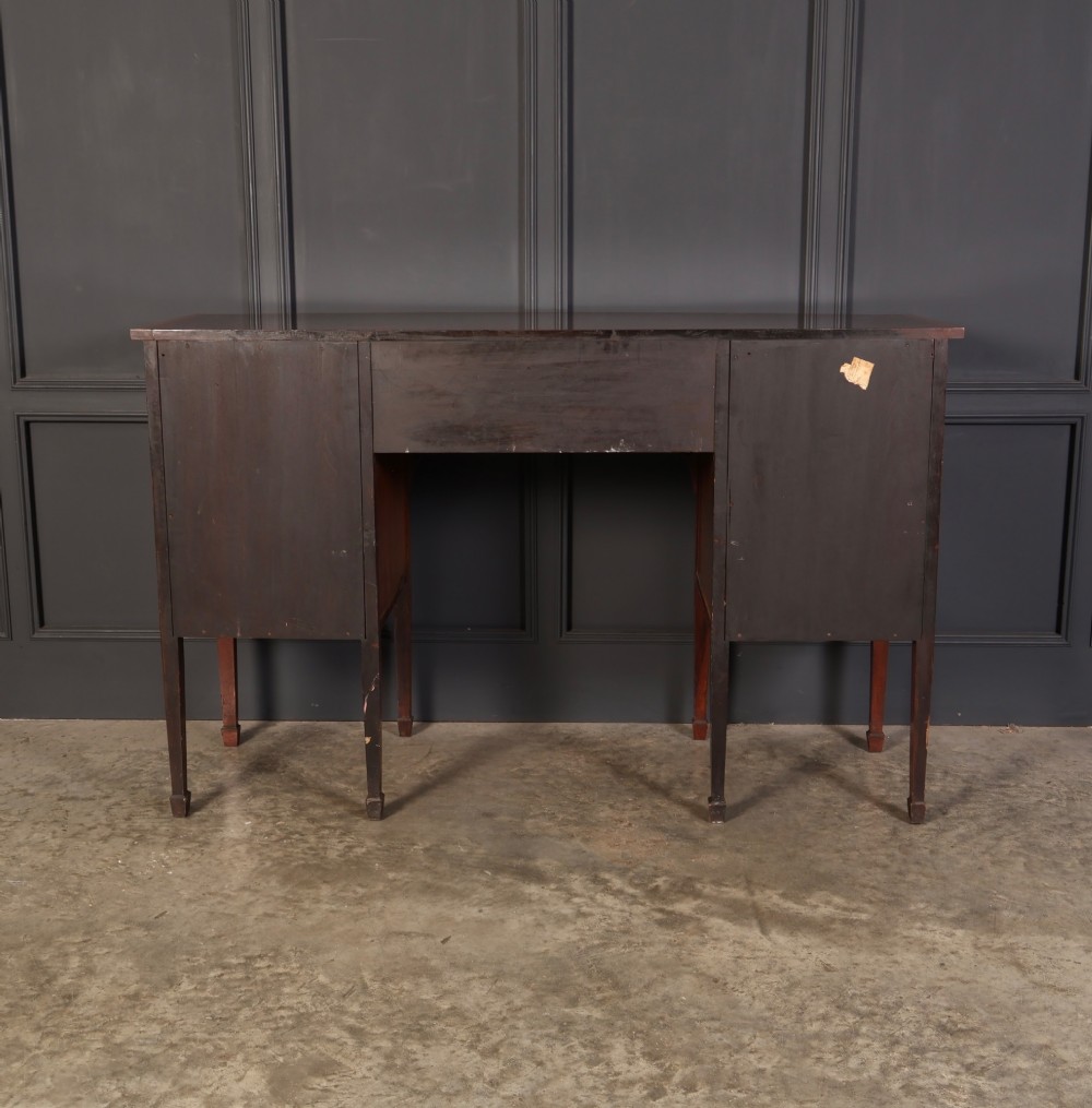 An antique bowfront mahogany sideboard featuring intricate urn marquetry inlays on cupboard doors, a central drawer, and slender square tapered legs. View XII