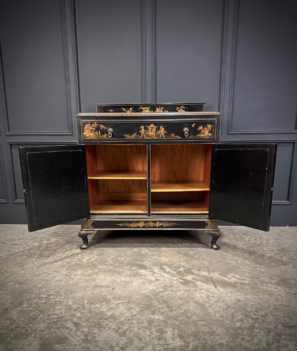 A black lacquered side cabinet decorated with gold chinoiserie landscape scenes, featuring one top drawer, double doors, and cabriole legs. View V