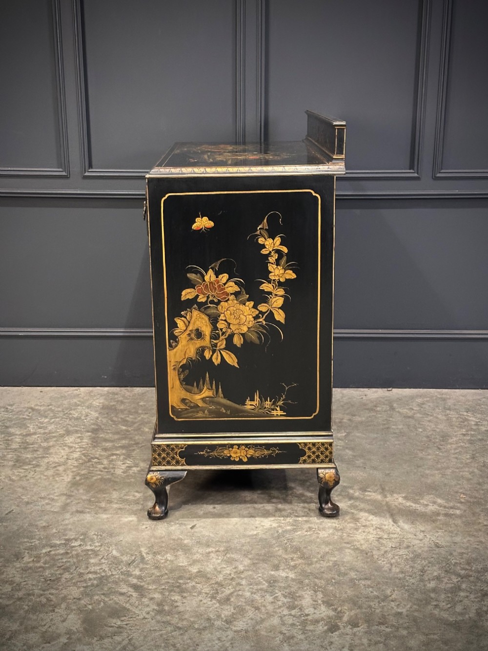 A black lacquered side cabinet decorated with gold chinoiserie landscape scenes, featuring one top drawer, double doors, and cabriole legs. View XI