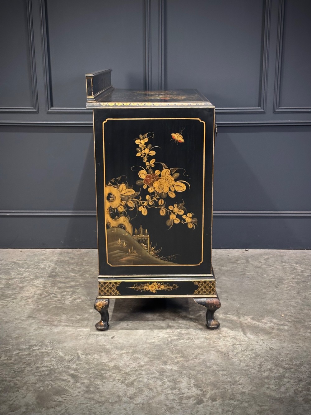 A black lacquered side cabinet decorated with gold chinoiserie landscape scenes, featuring one top drawer, double doors, and cabriole legs. View XIII