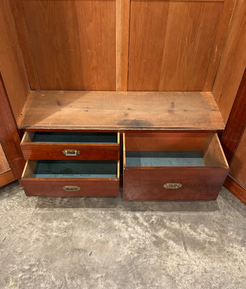 A Victorian mahogany double wardrobe featuring two arched panel doors with carved crest details, a flared top cornice, and a solid plinth base. View IV