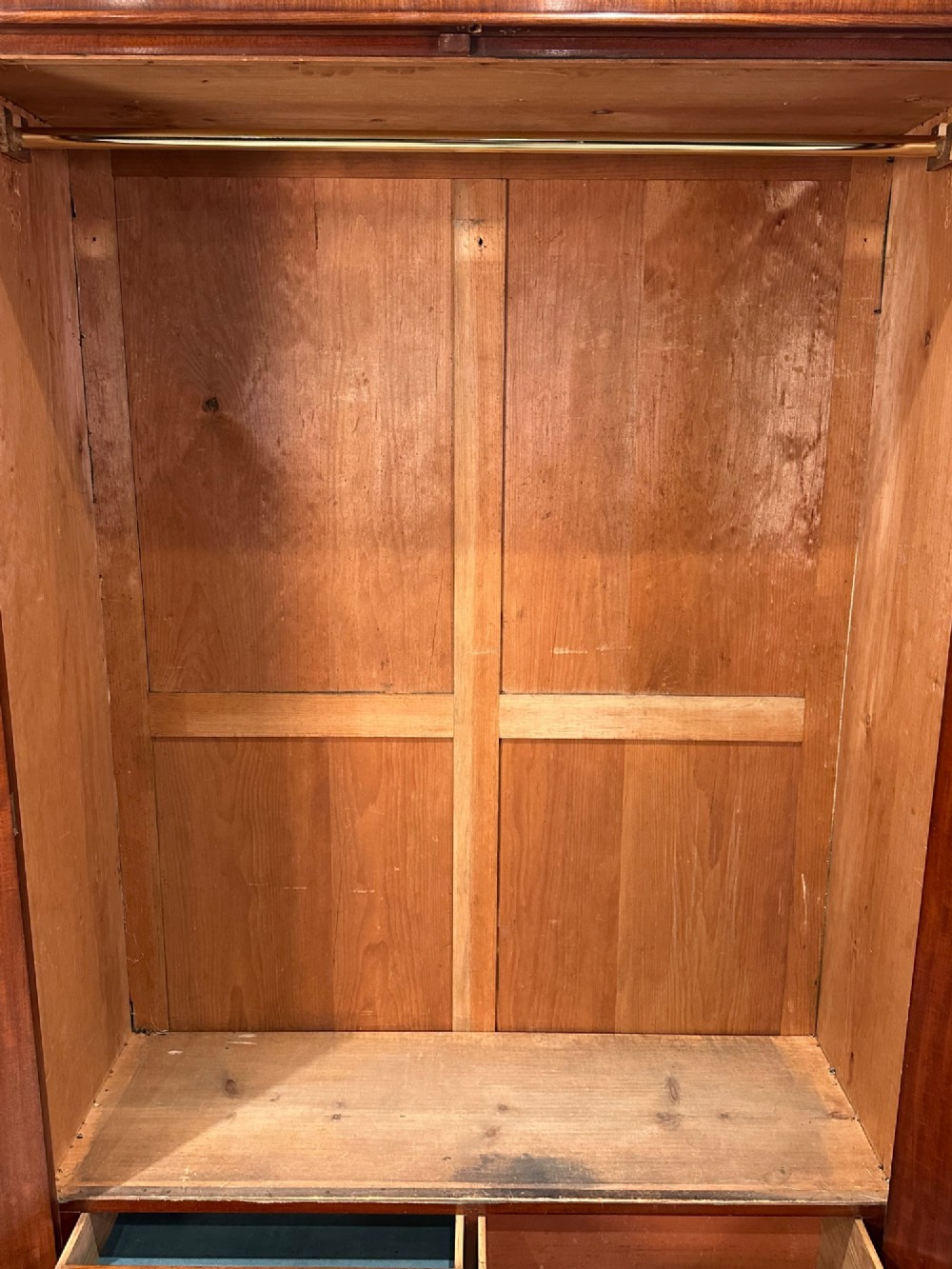 A Victorian mahogany double wardrobe featuring two arched panel doors with carved crest details, a flared top cornice, and a solid plinth base. View V