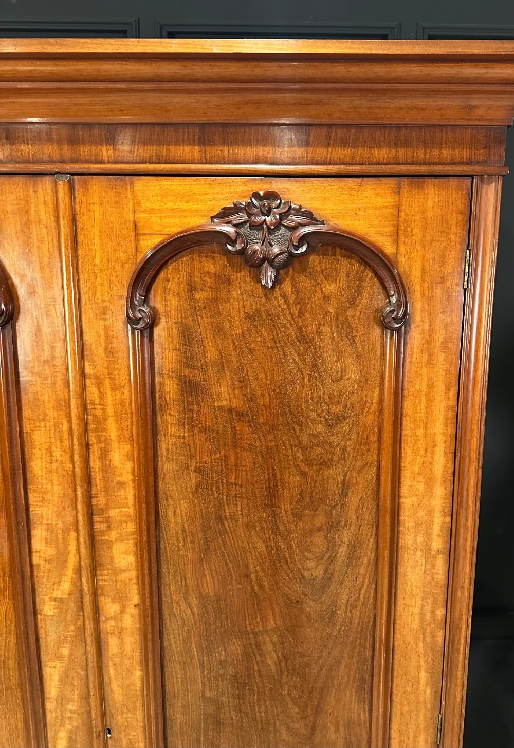 A Victorian mahogany double wardrobe featuring two arched panel doors with carved crest details, a flared top cornice, and a solid plinth base. View VI