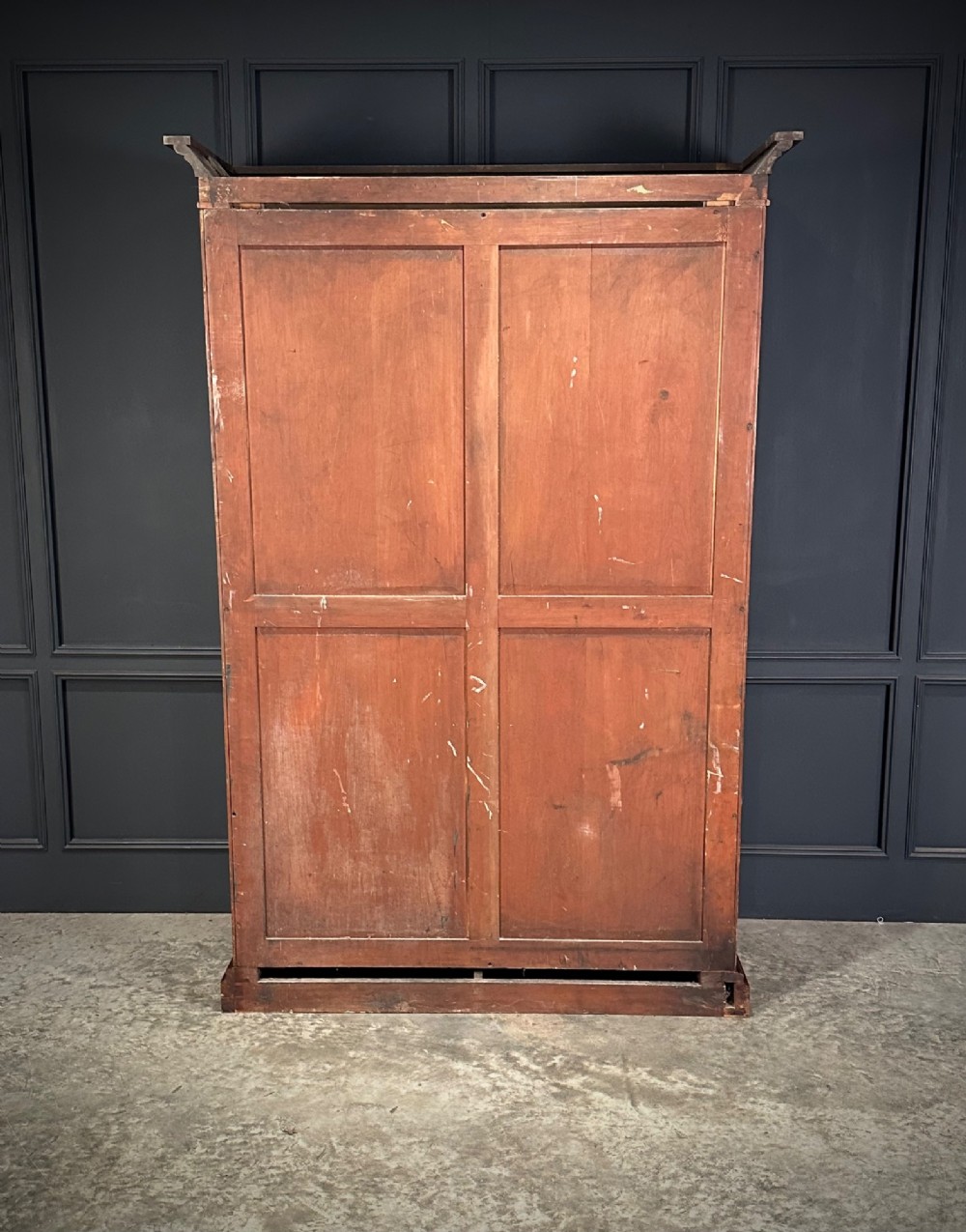 A Victorian mahogany double wardrobe featuring two arched panel doors with carved crest details, a flared top cornice, and a solid plinth base. View IX