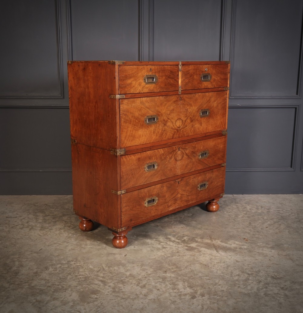 A Victorian figured walnut military campaign chest featuring two stackable sections, flush brass handles, brass corner strapping, and turned feet. View II