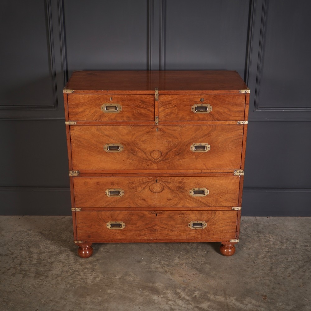 A Victorian figured walnut military campaign chest featuring two stackable sections, flush brass handles, brass corner strapping, and turned feet. View IV
