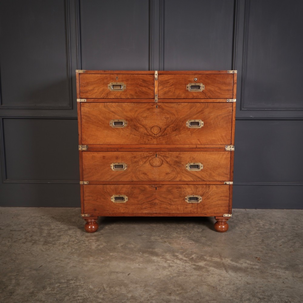 A Victorian figured walnut military campaign chest featuring two stackable sections, flush brass handles, brass corner strapping, and turned feet. View V