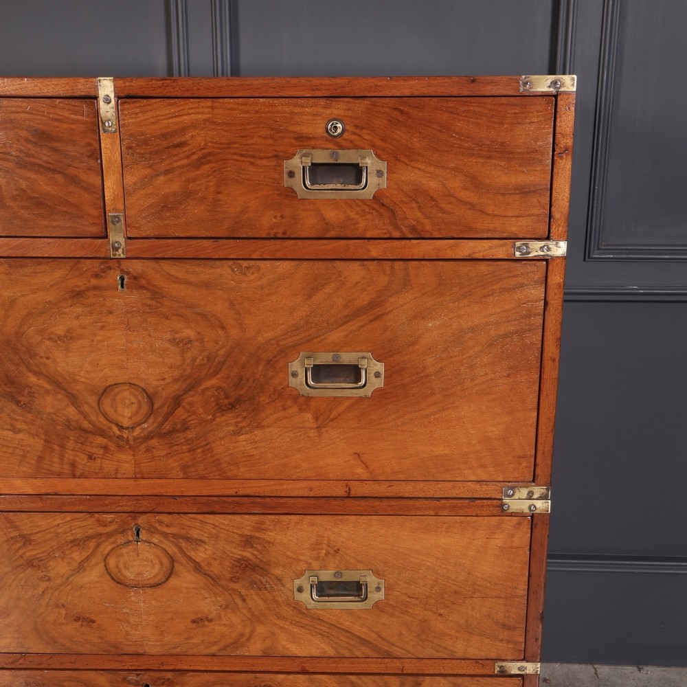 A Victorian figured walnut military campaign chest featuring two stackable sections, flush brass handles, brass corner strapping, and turned feet. View VI