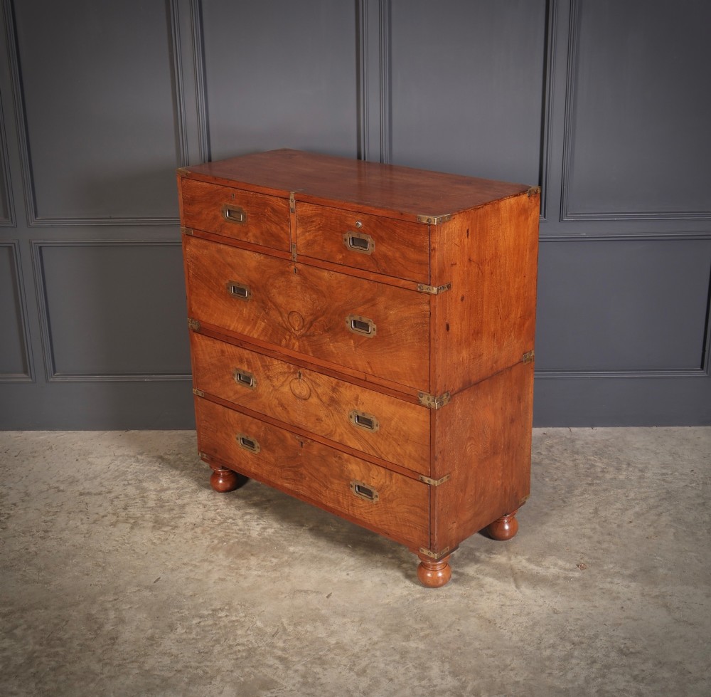 A Victorian figured walnut military campaign chest featuring two stackable sections, flush brass handles, brass corner strapping, and turned feet. View VIII