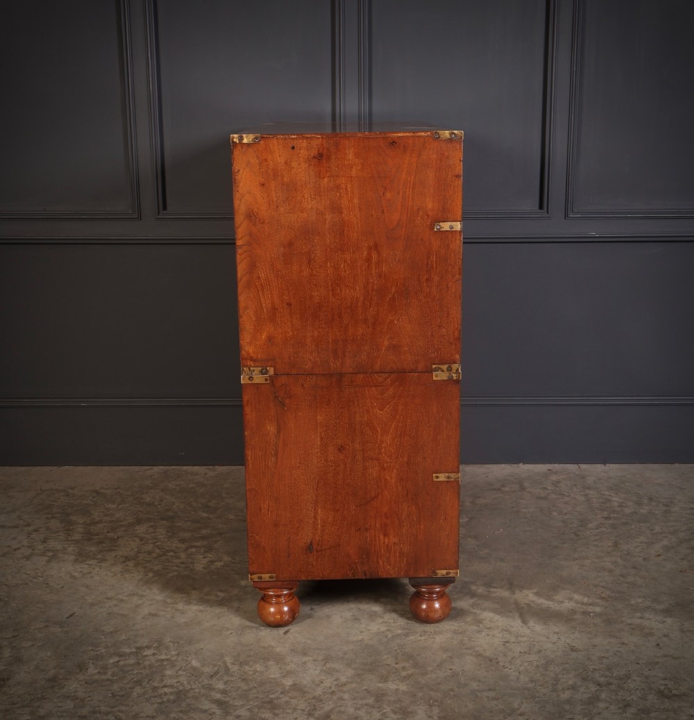 A Victorian figured walnut military campaign chest featuring two stackable sections, flush brass handles, brass corner strapping, and turned feet. View XII