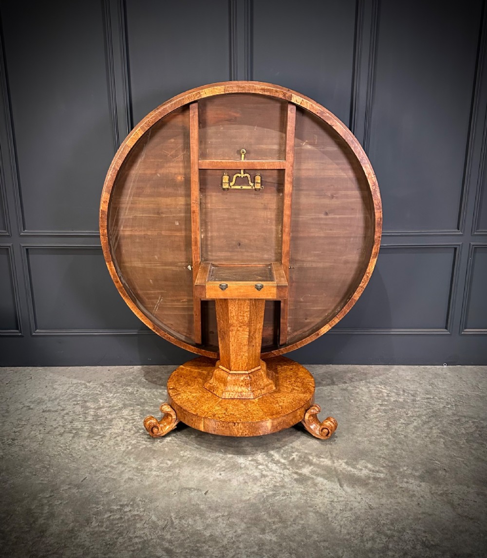 A round antique pollard oak breakfast table featuring a radial veneer pattern, faceted pedestal column, platform base, and four scroll feet. View VIII