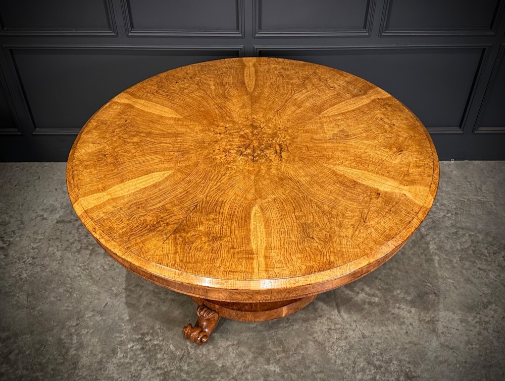A round antique pollard oak breakfast table featuring a radial veneer pattern, faceted pedestal column, platform base, and four scroll feet. View X