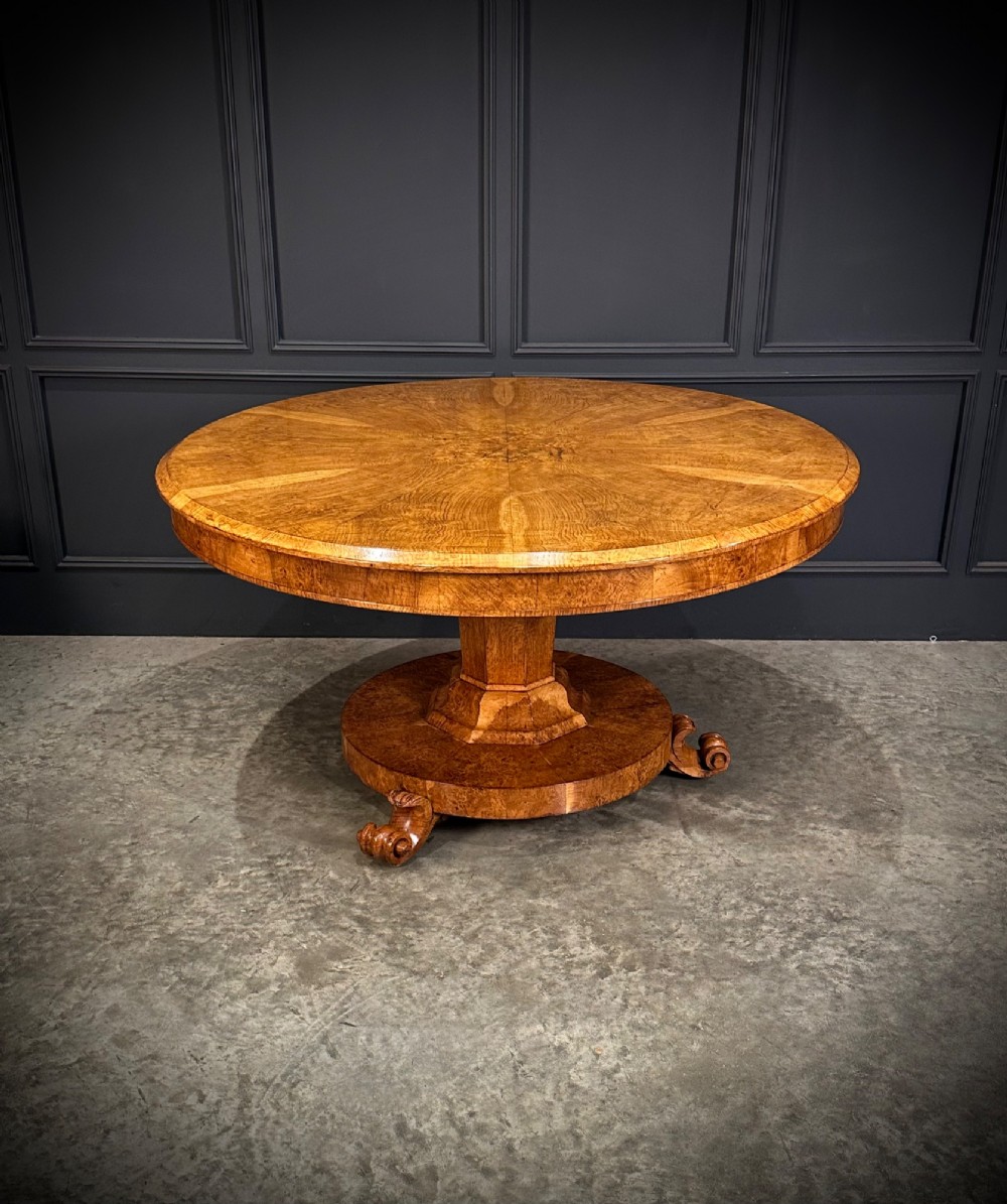 A round antique pollard oak breakfast table featuring a radial veneer pattern, faceted pedestal column, platform base, and four scroll feet. View XI