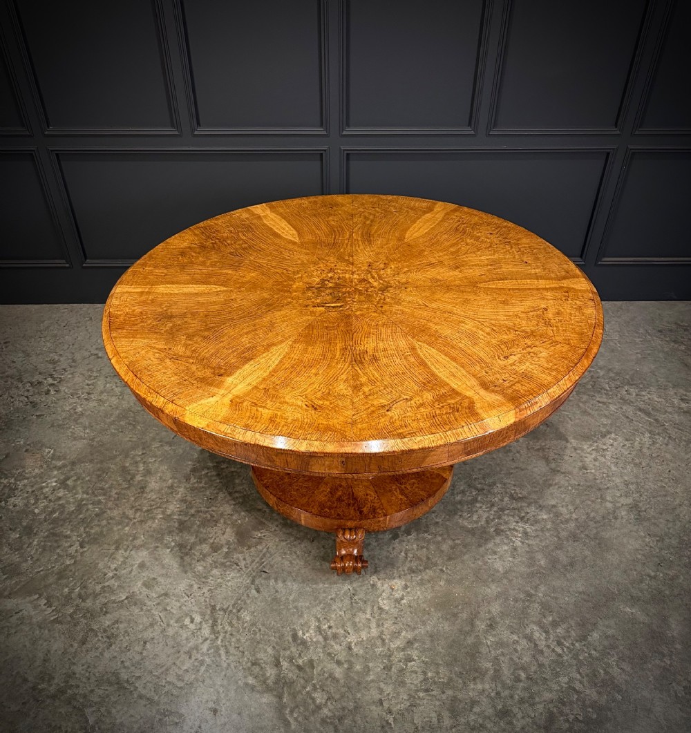 A round antique pollard oak breakfast table featuring a radial veneer pattern, faceted pedestal column, platform base, and four scroll feet. View XIII