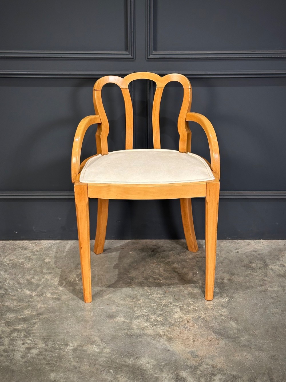 An Art Deco satinwood armchair featuring a triple-arched back rest, curved sweeping arms, a light cream upholstered seat pad, and tapered legs. View III