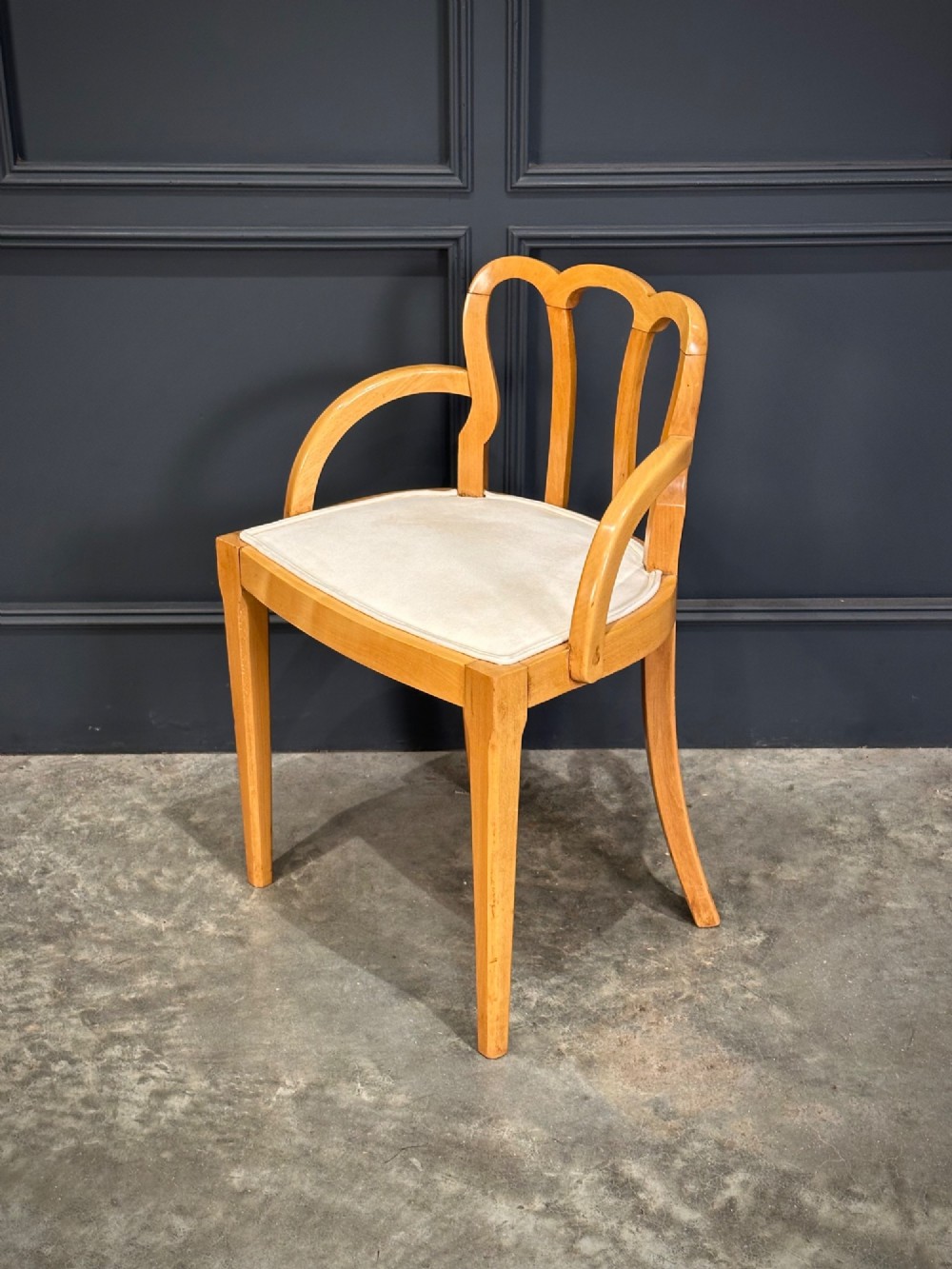 An Art Deco satinwood armchair featuring a triple-arched back rest, curved sweeping arms, a light cream upholstered seat pad, and tapered legs. View IV
