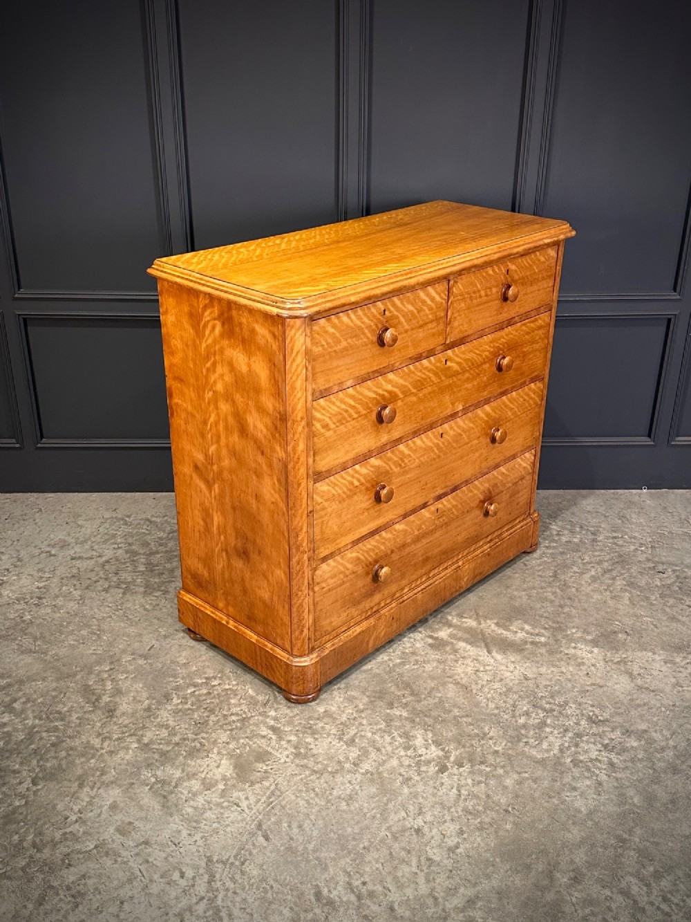 A Victorian satinwood chest of drawers featuring two short drawers over three long drawers with turned wooden knobs and a solid plinth base. View II