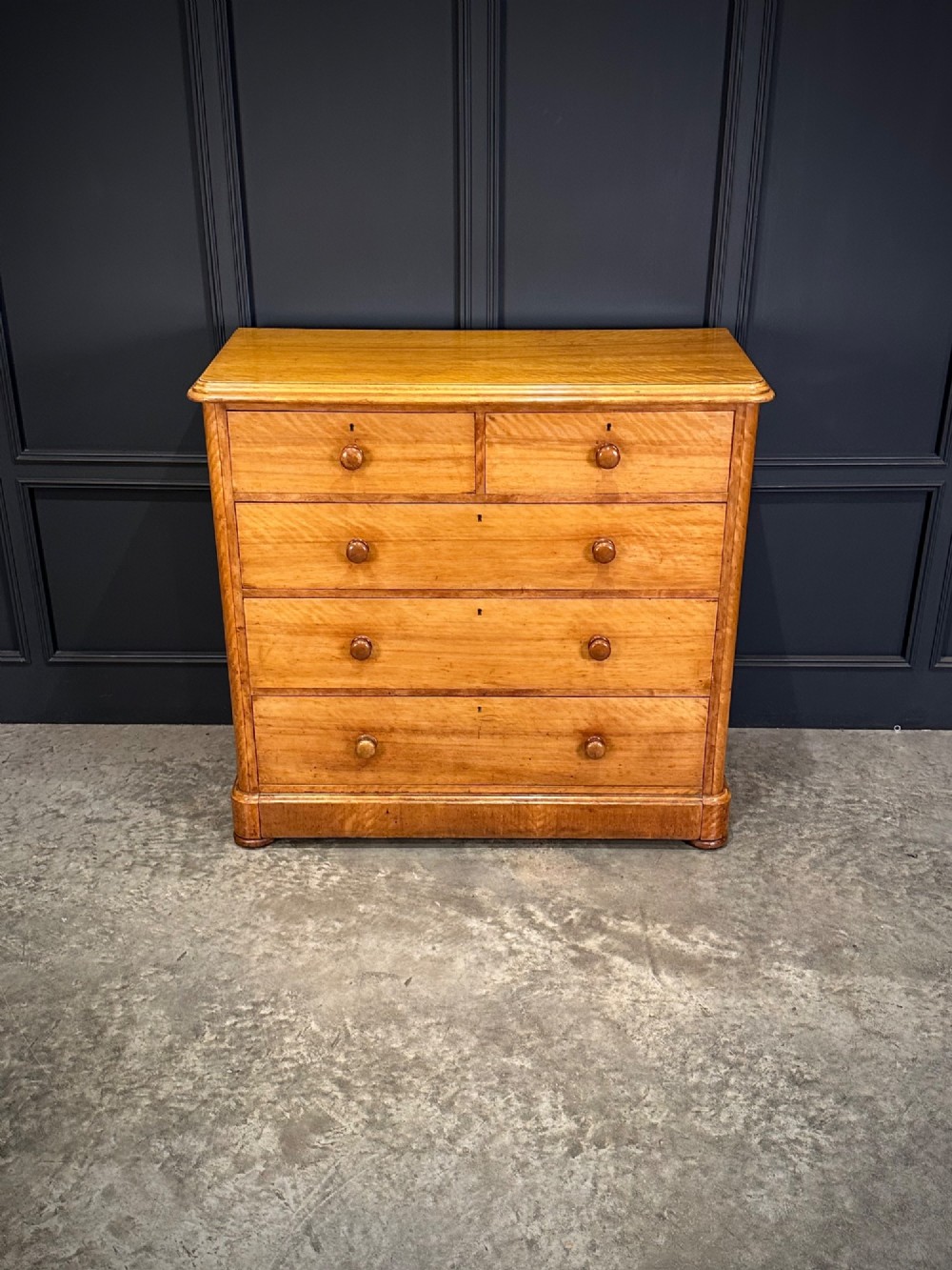 A Victorian satinwood chest of drawers featuring two short drawers over three long drawers with turned wooden knobs and a solid plinth base. View III