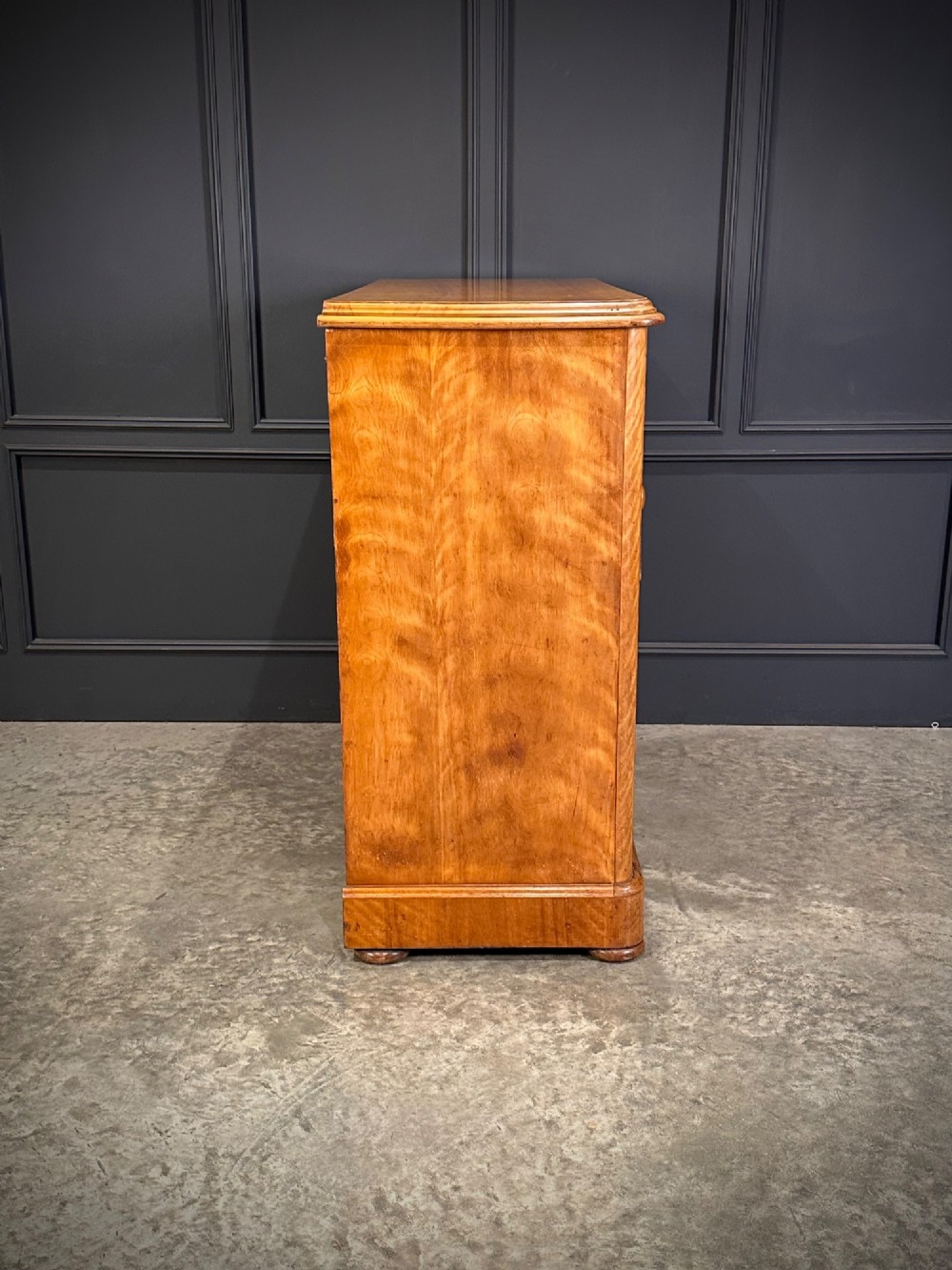 A Victorian satinwood chest of drawers featuring two short drawers over three long drawers with turned wooden knobs and a solid plinth base. View IX