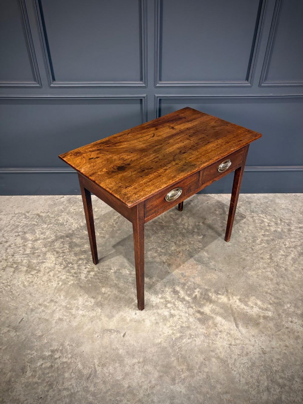 A Georgian mahogany side table featuring two front drawers with oval brass handles and straight square tapered legs. View II