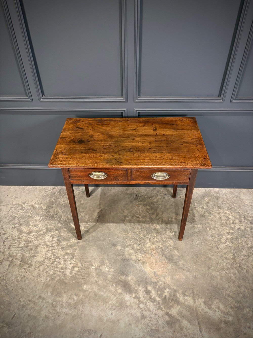 A Georgian mahogany side table featuring two front drawers with oval brass handles and straight square tapered legs. View IV