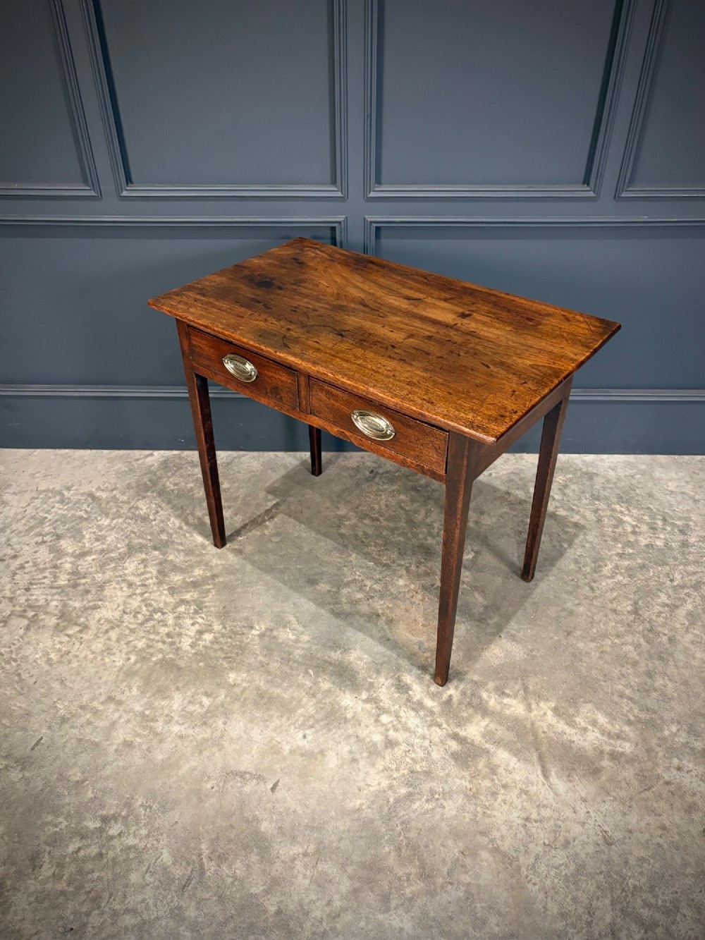 A Georgian mahogany side table featuring two front drawers with oval brass handles and straight square tapered legs. View V