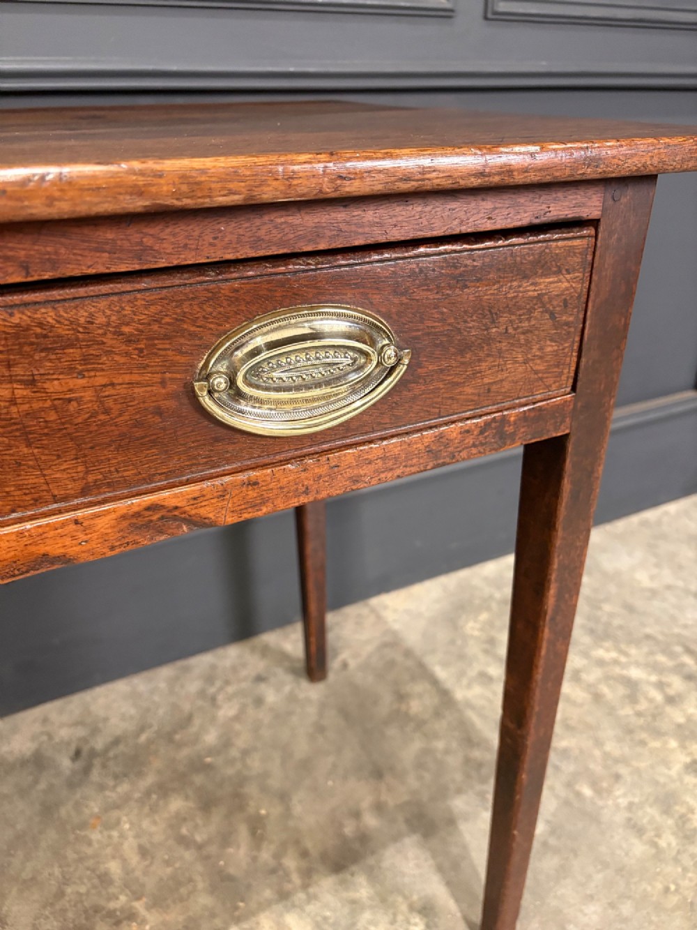 A Georgian mahogany side table featuring two front drawers with oval brass handles and straight square tapered legs. View XI
