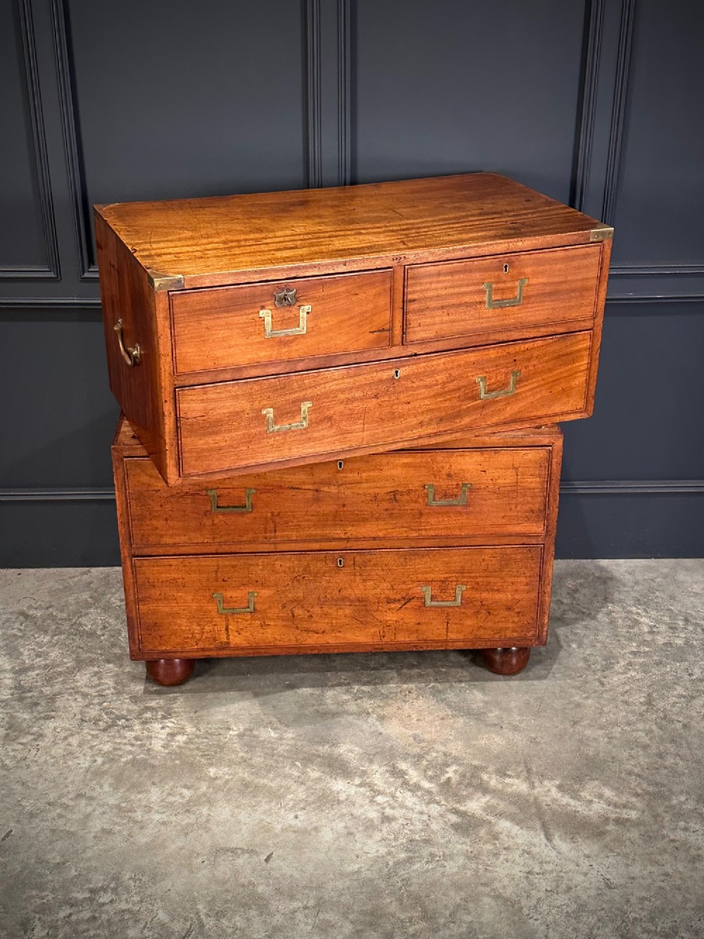 A Victorian two-part mahogany military campaign chest featuring flush brass handles, brass corner mounts, and turned bun feet. View V