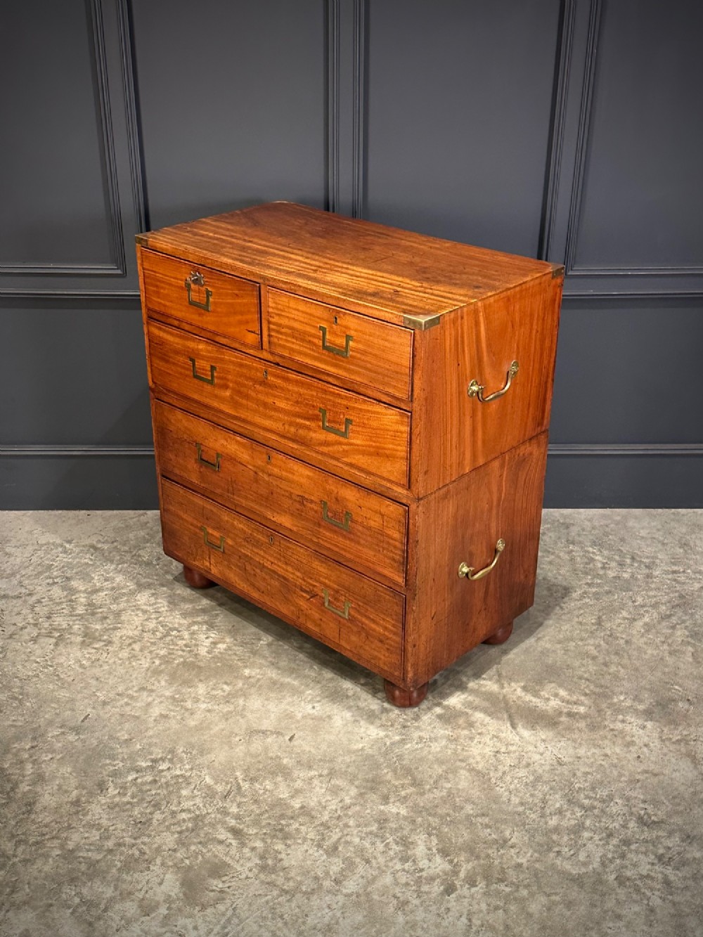A Victorian two-part mahogany military campaign chest featuring flush brass handles, brass corner mounts, and turned bun feet. View VII