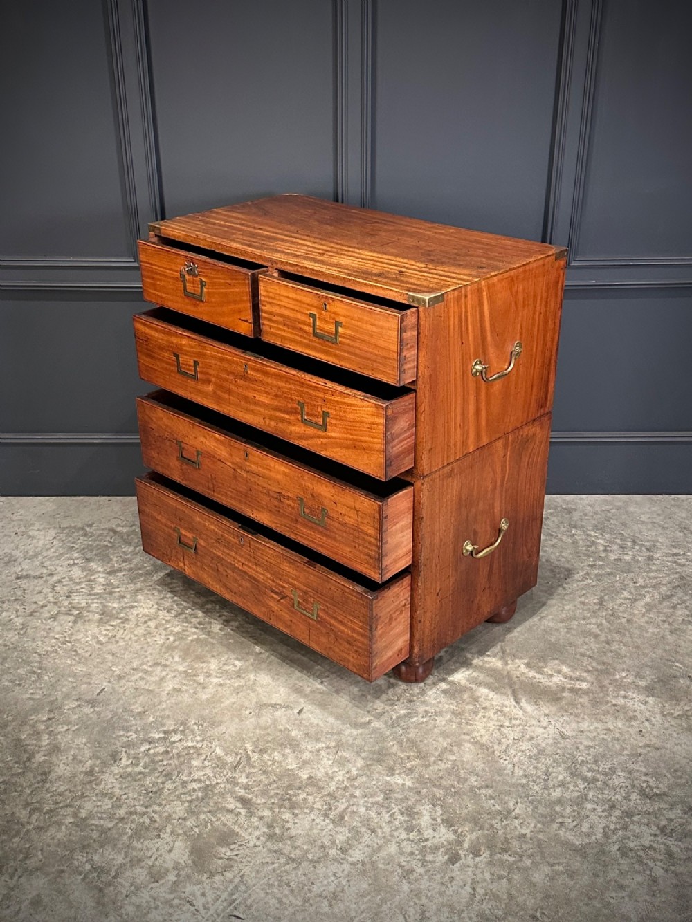 A Victorian two-part mahogany military campaign chest featuring flush brass handles, brass corner mounts, and turned bun feet. View VIII