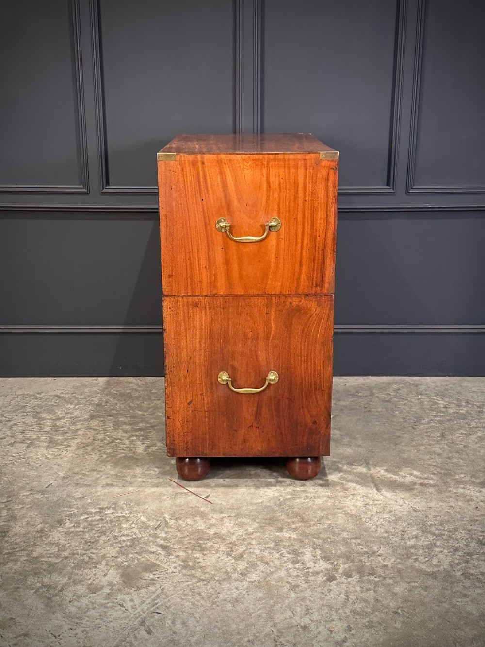 A Victorian two-part mahogany military campaign chest featuring flush brass handles, brass corner mounts, and turned bun feet. View IX