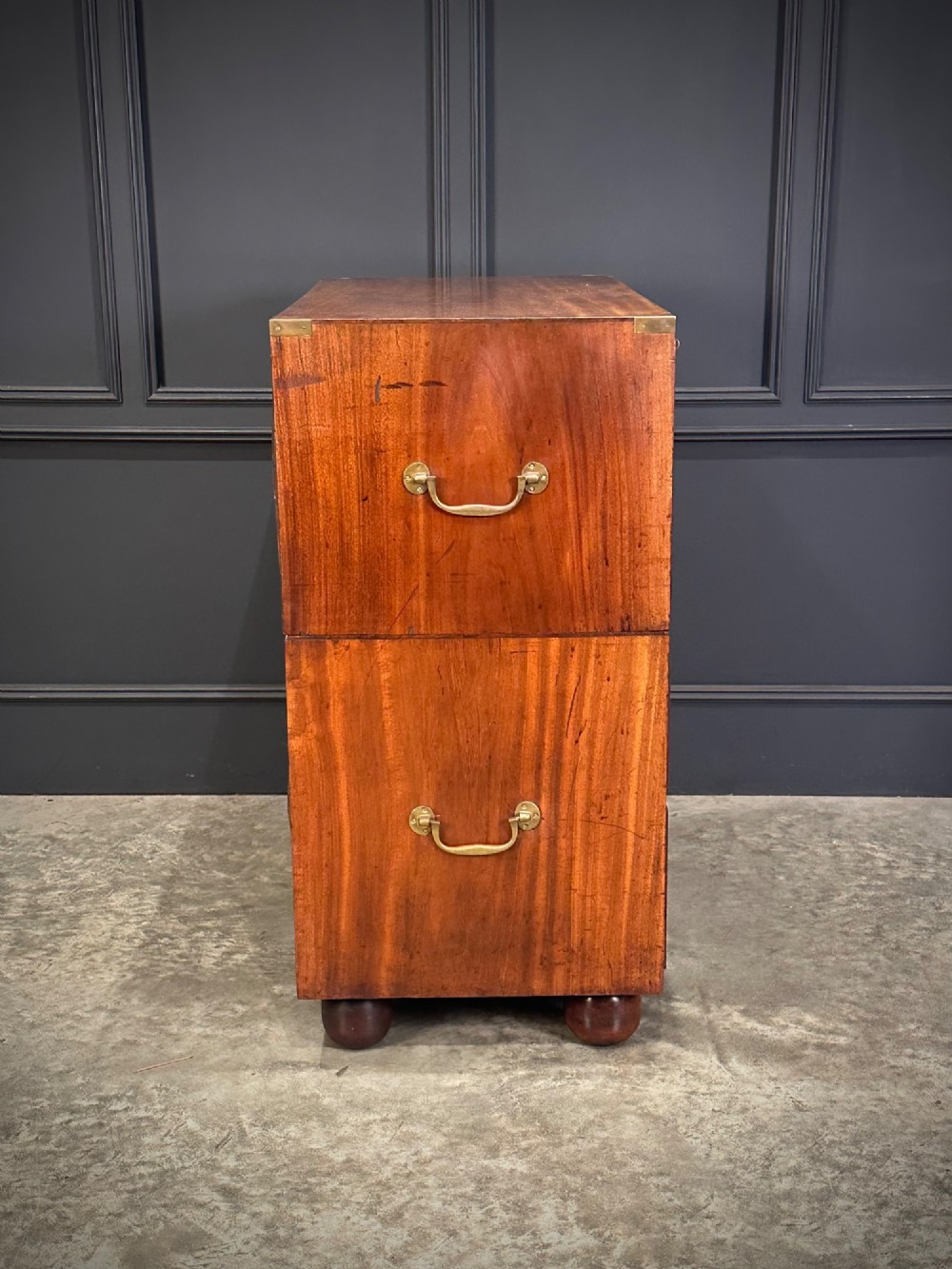 A Victorian two-part mahogany military campaign chest featuring flush brass handles, brass corner mounts, and turned bun feet. View XI
