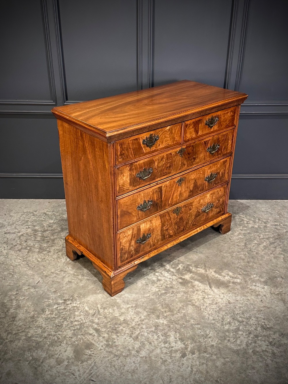 An 18th-century walnut chest of drawers featuring two short drawers over three long drawers, brass handles, and bracket feet. View II