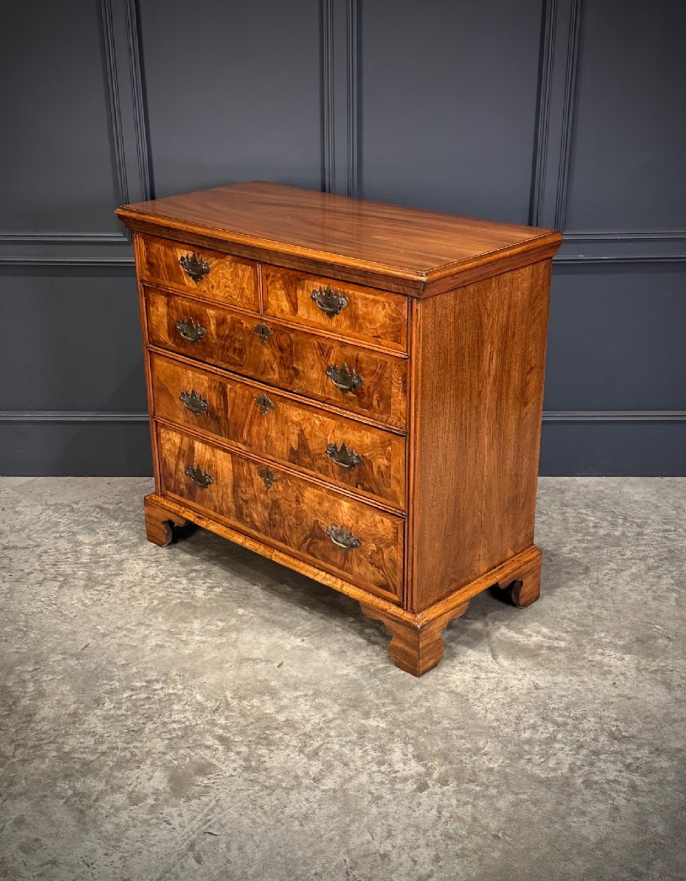 An 18th-century walnut chest of drawers featuring two short drawers over three long drawers, brass handles, and bracket feet. View IV