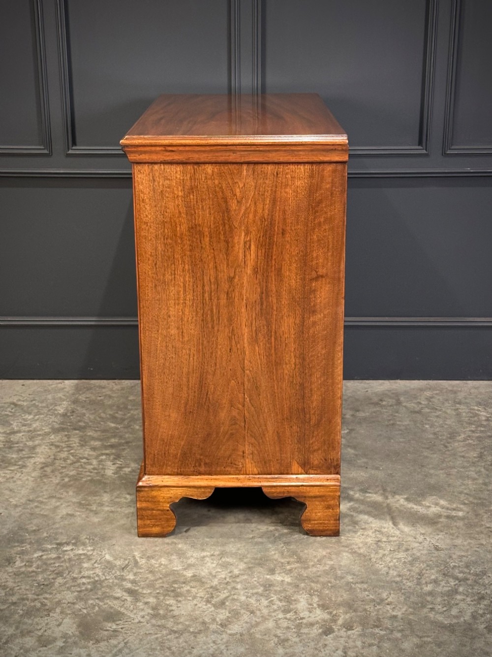 An 18th-century walnut chest of drawers featuring two short drawers over three long drawers, brass handles, and bracket feet. View VII