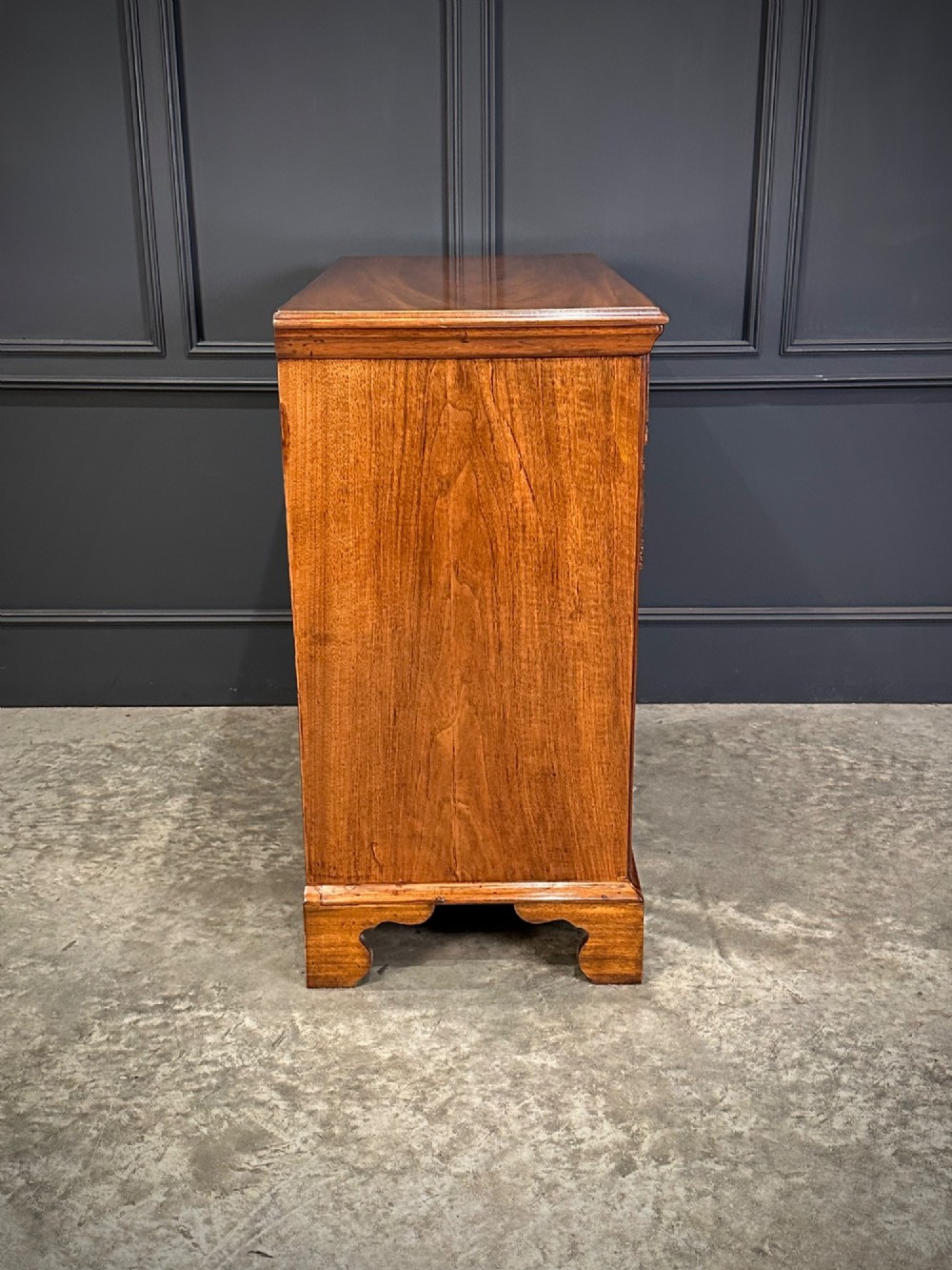 An 18th-century walnut chest of drawers featuring two short drawers over three long drawers, brass handles, and bracket feet. View IX