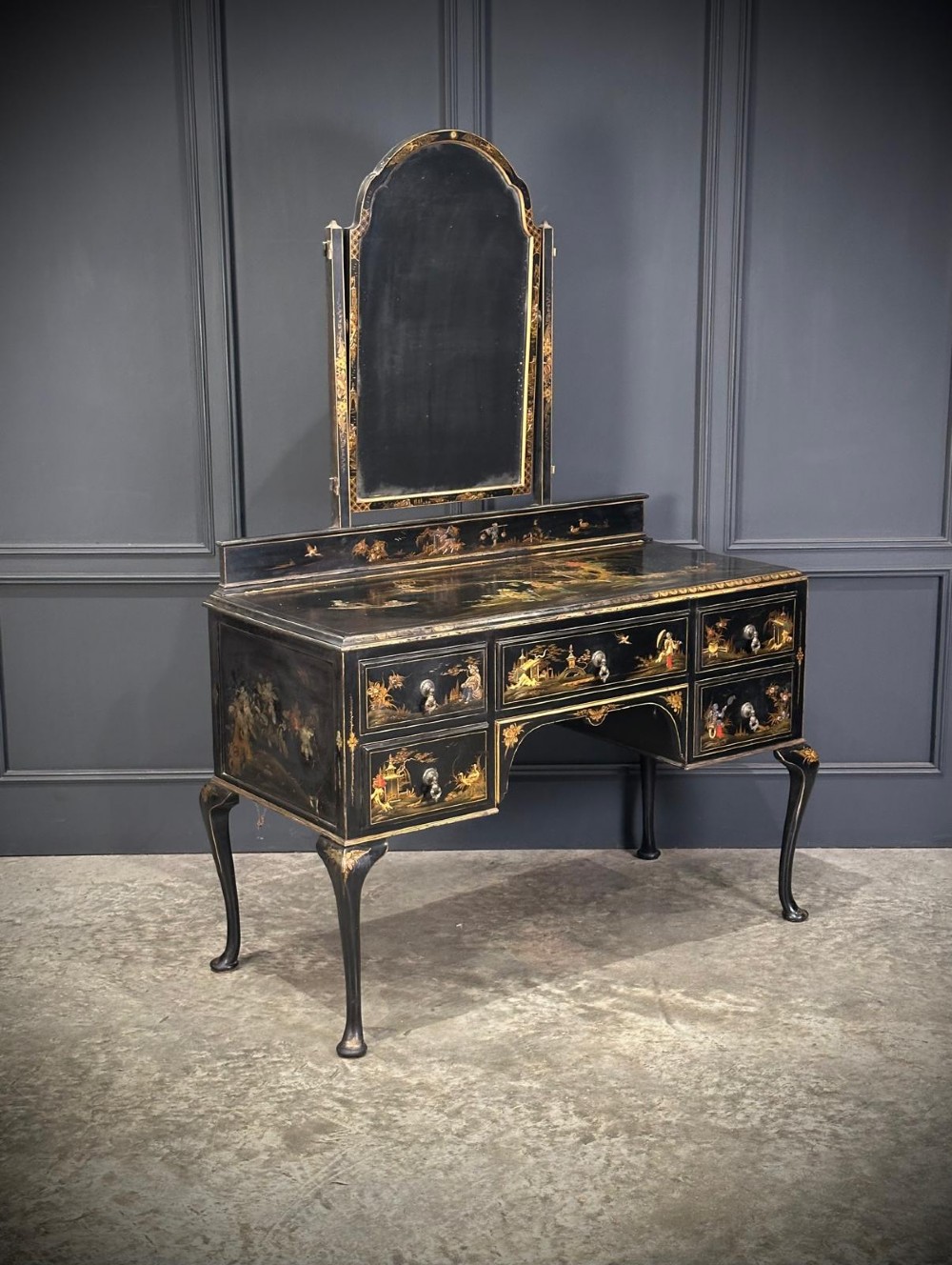 A black lacquered Chinoiserie dressing table featuring gilt hand-painted figures and landscapes, five drawers, cabriole legs, and an arched mirror attached to the top. View II