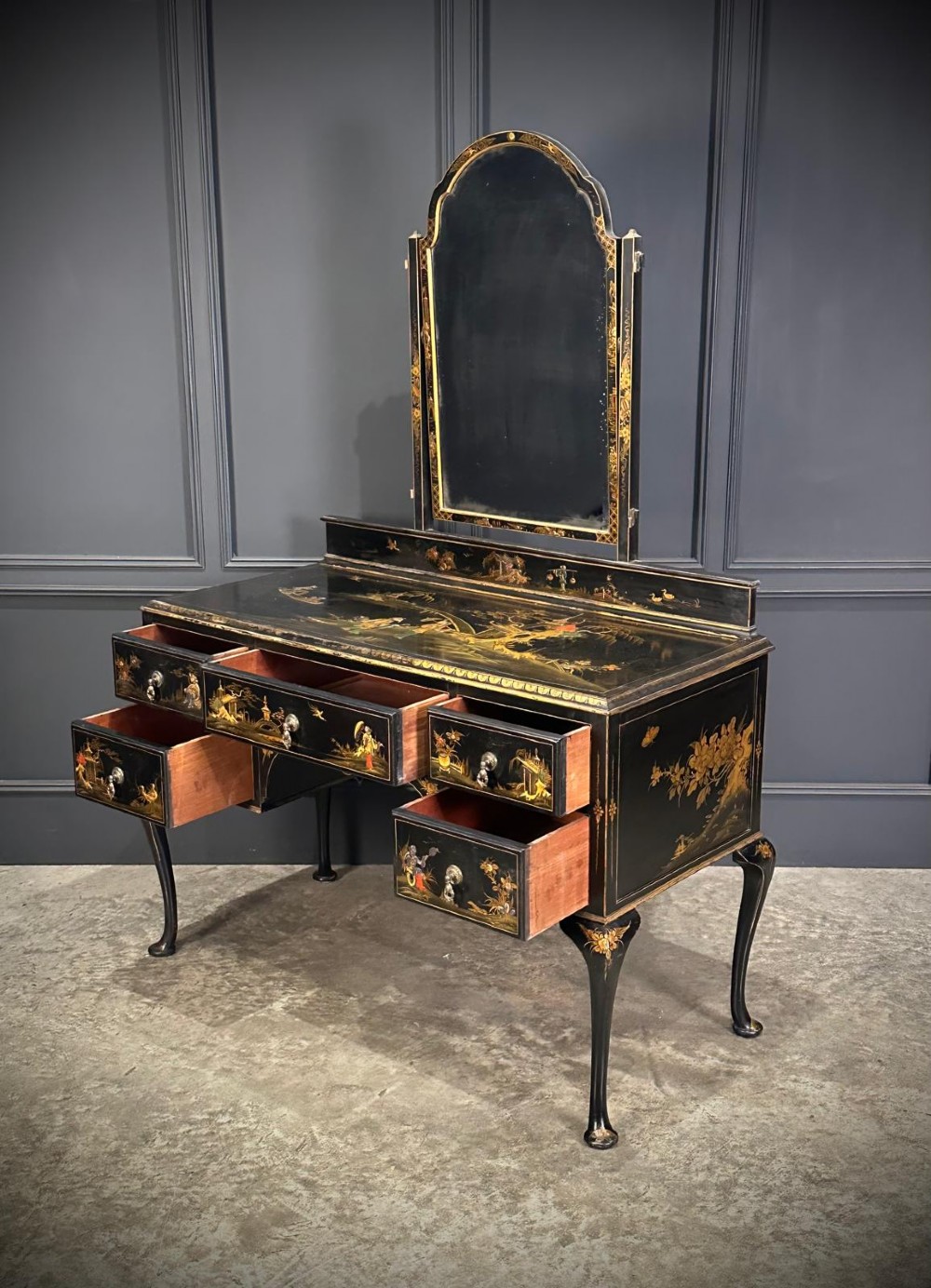 A black lacquered Chinoiserie dressing table featuring gilt hand-painted figures and landscapes, five drawers, cabriole legs, and an arched mirror attached to the top. View V