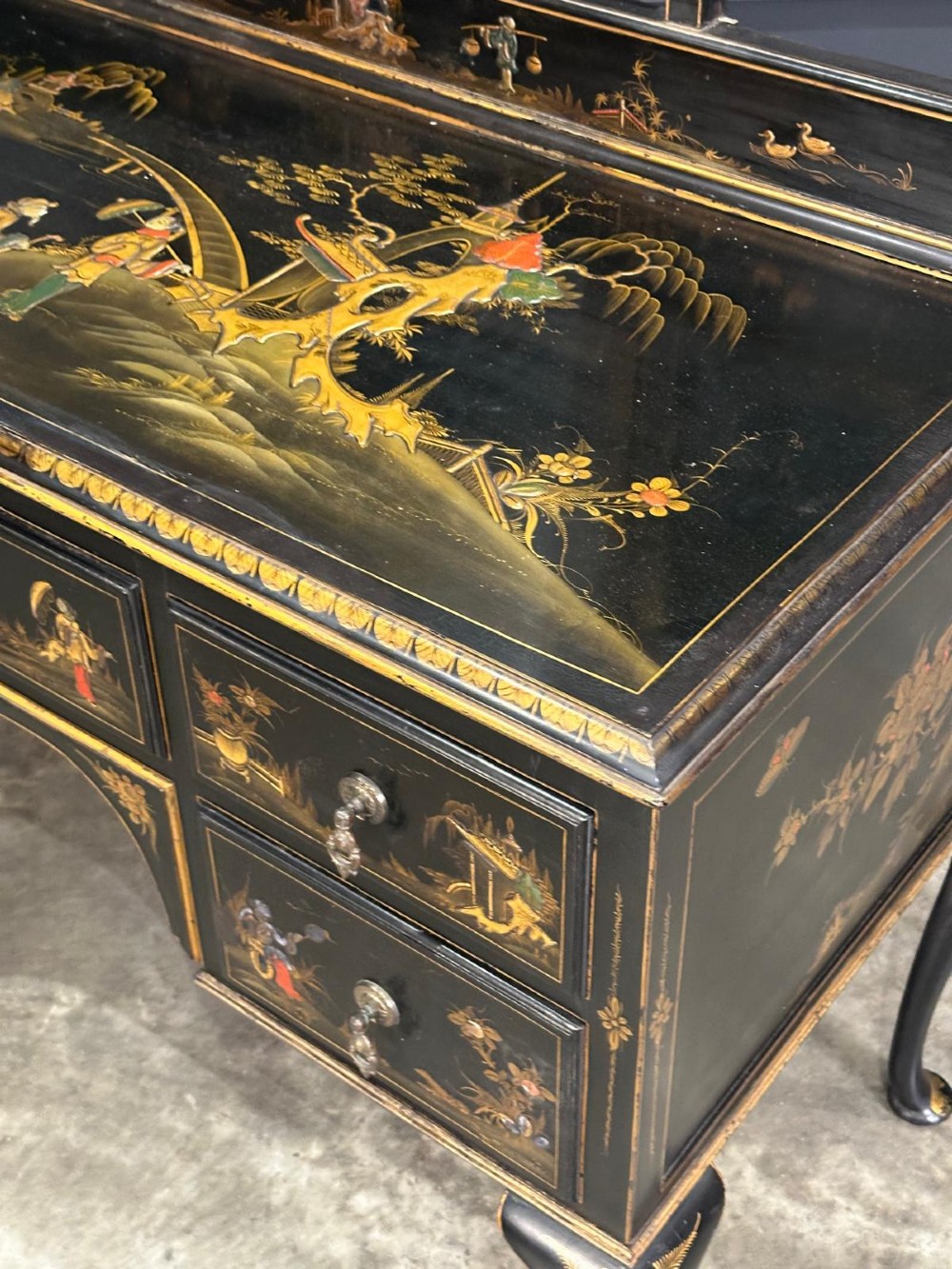 A black lacquered Chinoiserie dressing table featuring gilt hand-painted figures and landscapes, five drawers, cabriole legs, and an arched mirror attached to the top. View VIII