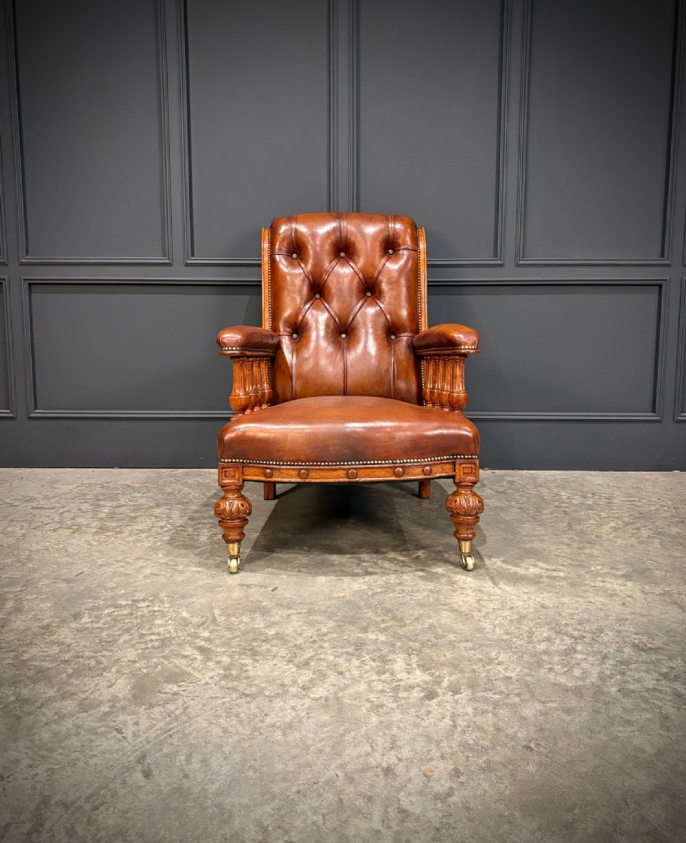 A pair of antique oak armchairs upholstered in deep-buttoned chestnut brown leather with turned front legs and brass castors. View IV